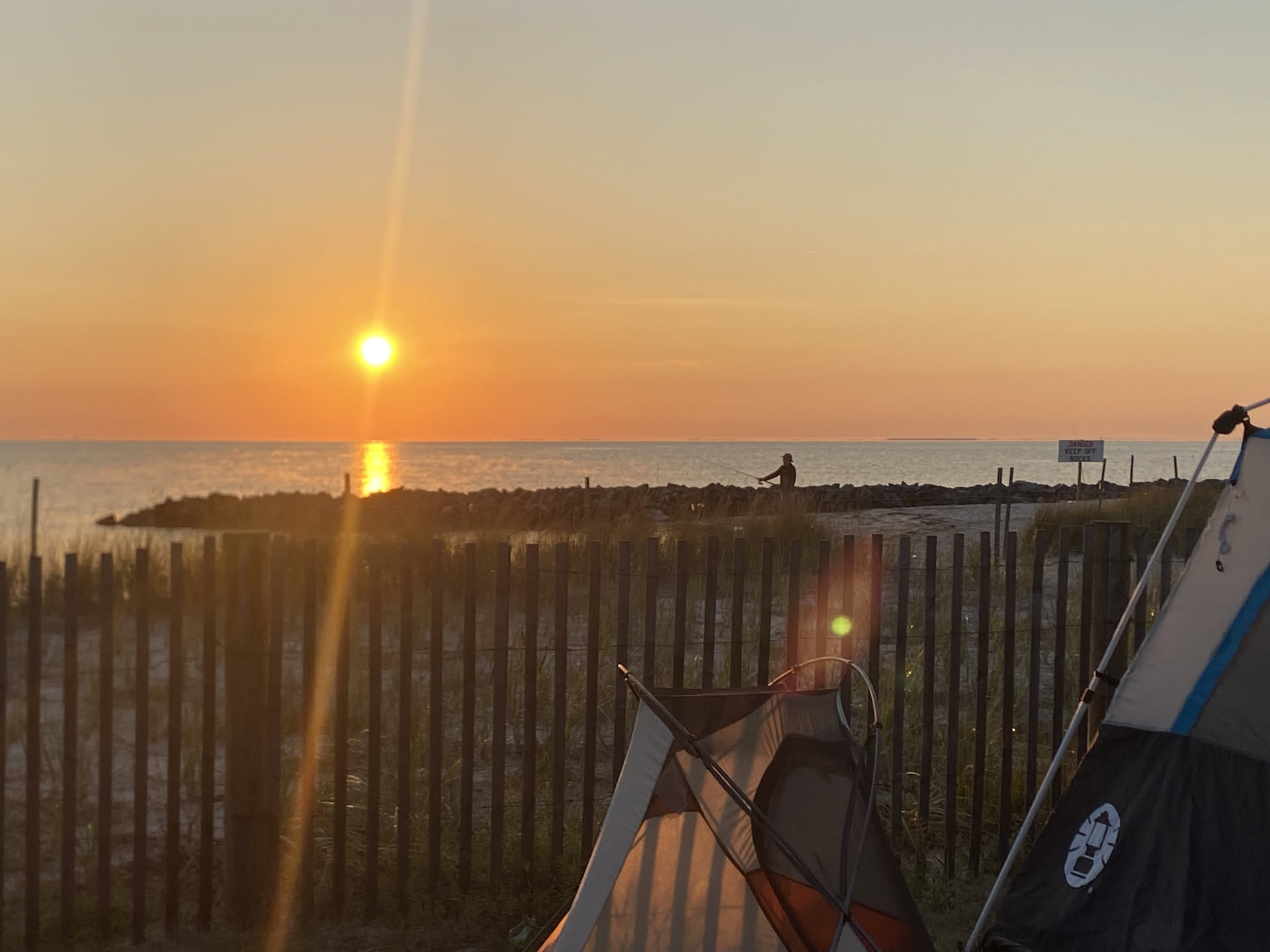 The sun rising over the Chesapeake Bay beyond the campground fence